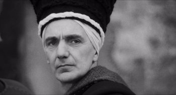 Movie still from “The Gospel According to St. Matthew” (1964), directed by Pier Paolo Pasolini – An old man with a hat on his head; Close Up shot, Low angle