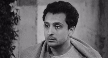 Movie still from “The Gospel According to St. Matthew” (1964), directed by Pier Paolo Pasolini – Black and white photograph of a man with a towel around his neck; Close Up shot, High angle