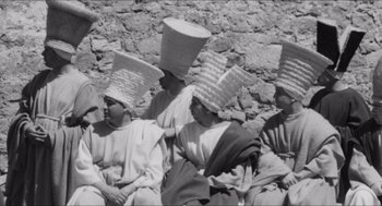 Movie still from “The Gospel According to St. Matthew” (1964), directed by Pier Paolo Pasolini – A black and white photo of a group of people with hats on their heads; Medium shot, Low angle