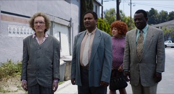 Movie still from “The Greasy Strangler” (2016), directed by Jim Hosking – A group of people walking down a street; Medium shot, Low angle
