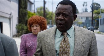 Movie still from “The Greasy Strangler” (2016), directed by Jim Hosking – A man and a woman are standing together; Close Up shot, Over the shoulder angle