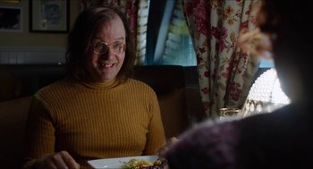 Movie still from “The Greasy Strangler” (2016), directed by Jim Hosking – An older woman sitting at a table with a plate of food in front of her; Close Up shot, Over the shoulder angle