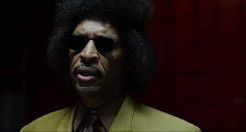 Movie still from “The Greasy Strangler” (2016), directed by Jim Hosking – A person wearing a suit and sunglasses; Close Up shot, Low angle