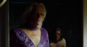 Movie still from “The Greasy Strangler” (2016), directed by Jim Hosking – An older woman in a purple dress and a younger woman in a purple dress; Close Up shot, Over the shoulder angle