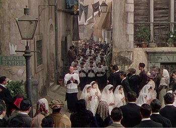 Movie still from “The Great Caruso” (1951), directed by Richard Thorpe – A group of people walking down a street; Extreme Wide shot, High angle