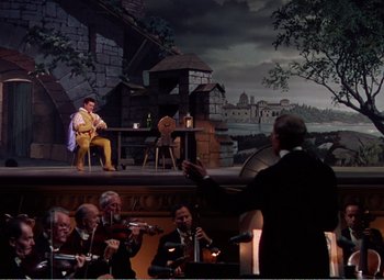 Movie still from “The Great Caruso” (1951), directed by Richard Thorpe – A group of people sitting in front of an orchestra; Extreme Wide shot, High angle