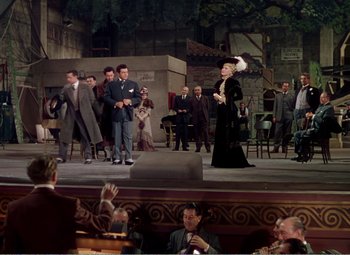 Movie still from “The Great Caruso” (1951), directed by Richard Thorpe – A woman in a black dress on a stage with people; Extreme Wide shot, High angle
