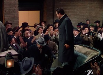 Movie still from “The Great Caruso” (1951), directed by Richard Thorpe – A group of men in suits and hats clapping at an event; Wide shot, High angle