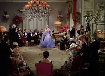 Movie still from “The Great Caruso” (1951), directed by Richard Thorpe – A group of people sitting in a room with a woman in a purple dress; Wide shot, High angle