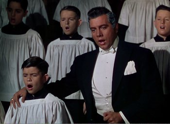 Movie still from “The Great Caruso” (1951), directed by Richard Thorpe – A group of men in suits singing in a choir; Medium shot, Low angle