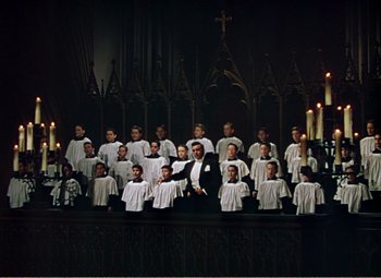 Movie still from “The Great Caruso” (1951), directed by Richard Thorpe – A group of young people in white robes standing in front of candles in a church; Wide shot, High angle