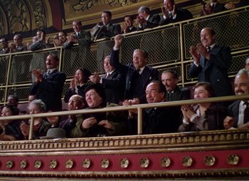 Movie still from “The Great Caruso” (1951), directed by Richard Thorpe – A group of people sitting in a theater with their hands raised; Wide shot, Low angle