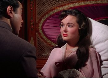 Movie still from “The Great Caruso” (1951), directed by Richard Thorpe – A woman in a pink dress talking to a man in a suit; Medium shot, Over the shoulder angle