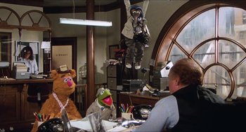 Movie still from “The Great Muppet Caper” (1981), directed by Jim Henson – A group of people sitting in a room with stuffed animals; Wide shot, Low angle