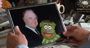 Movie still from “The Great Muppet Caper” (1981), directed by Jim Henson – A person holding a picture of kermit the frog; Extreme Close Up shot, Over the shoulder angle