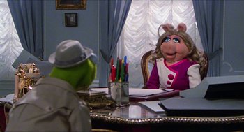 Movie still from “The Great Muppet Caper” (1981), directed by Jim Henson – A person sitting at a table in front of a muppet; Medium shot, Over the shoulder angle
