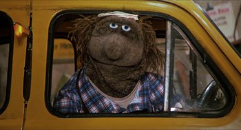 Movie still from “The Great Muppet Caper” (1981), directed by Jim Henson – A person in a car wearing a plaid shirt; Close Up shot, High angle