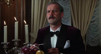 Movie still from “The Great Muppet Caper” (1981), directed by Jim Henson – A man sitting at a table with a knife in his mouth; Close Up shot, Low angle