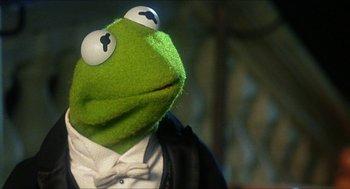 Movie still from “The Great Muppet Caper” (1981), directed by Jim Henson – The head of a kermit the frog puppet; Close Up shot, Over the shoulder angle