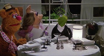 Movie still from “The Great Muppet Caper” (1981), directed by Jim Henson – A couple of people sitting at a dinner table; Medium shot, High angle