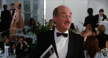 Movie still from “The Great Muppet Caper” (1981), directed by Jim Henson – A man in a suit and bow tie holding a book; Medium shot, Low angle