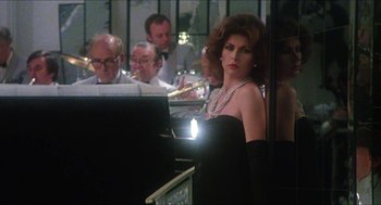Movie still from “The Great Muppet Caper” (1981), directed by Jim Henson – A woman in a black dress is playing the piano; Medium shot, Over the shoulder angle