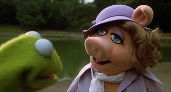 Movie still from “The Great Muppet Caper” (1981), directed by Jim Henson – A person dressed as kermit the frog and miss piggy; Close Up shot, Over the shoulder angle
