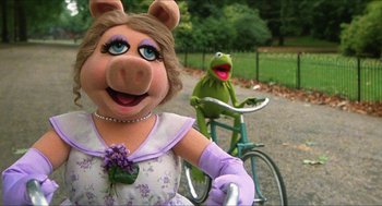 Movie still from “The Great Muppet Caper” (1981), directed by Jim Henson – A woman riding a bike next to kermit the frog on a bicycle; Close Up shot, High angle