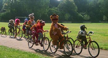 Movie still from “The Great Muppet Caper” (1981), directed by Jim Henson – A group of people dressed up as sesame street riding bikes; Extreme Wide shot, High angle