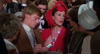 Movie still from “The Great Muppet Caper” (1981), directed by Jim Henson – A woman in a red dress and a red hat is looking at her cell phone; Close Up shot, Over the shoulder angle