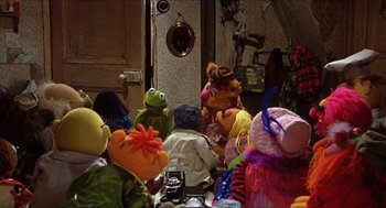 Movie still from “The Great Muppet Caper” (1981), directed by Jim Henson – A group of people sitting around a table with stuffed animals on it; Wide shot, High angle