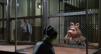 Movie still from “The Great Muppet Caper” (1981), directed by Jim Henson – Two men and a boy in a cage with a pig puppet; Wide shot, Over the shoulder angle