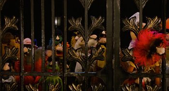 Movie still from “The Great Muppet Caper” (1981), directed by Jim Henson – A group of people standing behind a metal fence; Wide shot, High angle