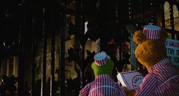 Movie still from “The Great Muppet Caper” (1981), directed by Jim Henson – A stuffed animal sitting in front of a metal fence; Medium shot, Over the shoulder angle