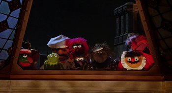 Movie still from “The Great Muppet Caper” (1981), directed by Jim Henson – A group of stuffed animals sitting on top of a wooden table; Wide shot, Low angle