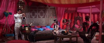 Movie still from “The Great Race” (1965), directed by Blake Edwards – A woman sitting on top of a bed wearing a top hat; Wide shot, High angle