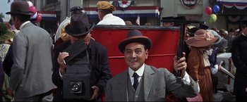 Movie still from “The Great Race” (1965), directed by Blake Edwards – A man in a suit and a hat sitting in a car; Medium shot, Low angle
