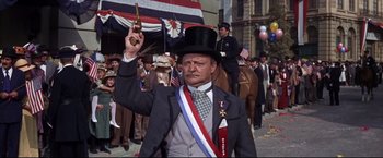 Movie still from “The Great Race” (1965), directed by Blake Edwards – A man wearing a top hat and a tie holding up a gun; Medium shot, Low angle