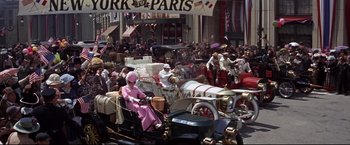 Movie still from “The Great Race” (1965), directed by Blake Edwards – A crowd of people riding on the back of an old fashioned car; Wide shot, High angle