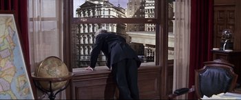 Movie still from “The Great Race” (1965), directed by Blake Edwards – A man in a suit leaning on a window ledge; Wide shot, Low angle