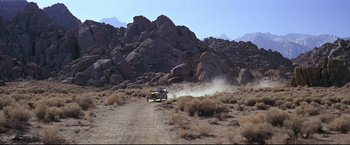 Movie still from “The Great Race” (1965), directed by Blake Edwards – A car driving down a dirt road in the middle of the desert; Extreme Wide shot, High angle