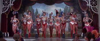 Movie still from “The Great Race” (1965), directed by Blake Edwards – A group of women in red and white outfits on a stage; Wide shot, Low angle