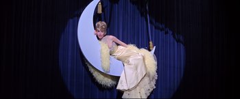 Movie still from “The Great Race” (1965), directed by Blake Edwards – A woman in a white dress is standing in front of a moon; Wide shot, Low angle