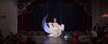 Movie still from “The Great Race” (1965), directed by Blake Edwards – A woman in a costume on a runway in front of a crowd; Wide shot, Low angle