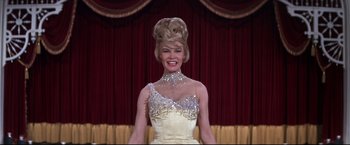 Movie still from “The Great Race” (1965), directed by Blake Edwards – A woman in a white dress with a big smile on her face; Medium shot, Low angle