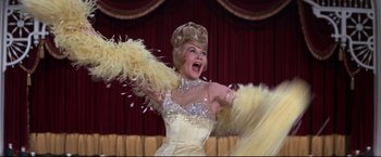 Movie still from “The Great Race” (1965), directed by Blake Edwards – A woman in a white dress holding a feather duster; Medium shot, Low angle