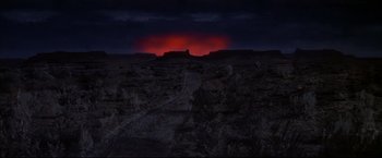 Movie still from “The Great Race” (1965), directed by Blake Edwards – A red glow is seen in the distance from a hill; Extreme Wide shot, High angle