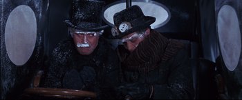 Movie still from “The Great Race” (1965), directed by Blake Edwards – A couple of men sitting next to each other on a bench; Medium shot, Low angle