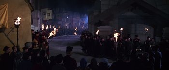 Movie still from “The Great Race” (1965), directed by Blake Edwards – A group of people standing next to each other holding torches; Wide shot, High angle