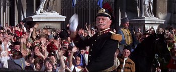 Movie still from “The Great Race” (1965), directed by Blake Edwards – A man in a military uniform holding a sheet of paper in front of a crowd of onlookers; Medium shot, Low angle